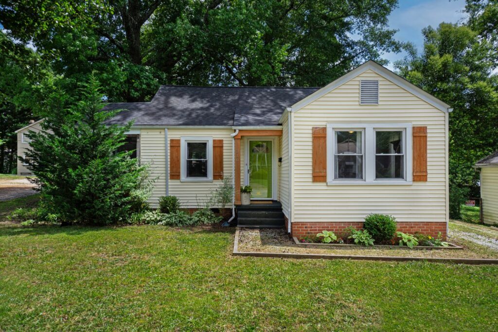 Small cottage with a green front door and a brick-edged garden bed