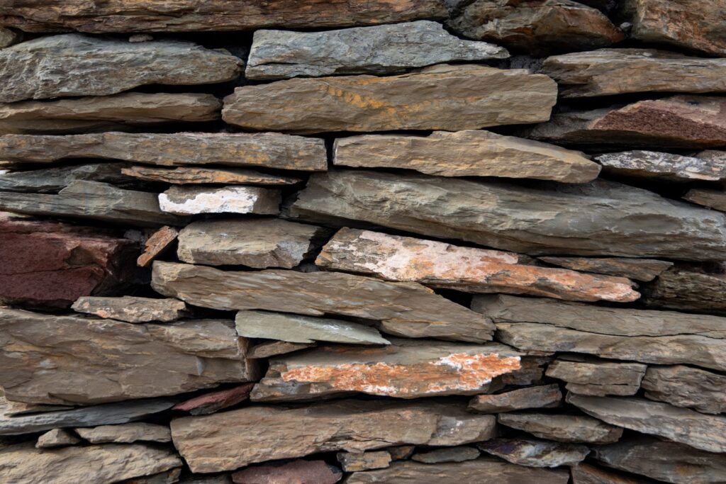 Close-up of a dry-stacked natural stone wall in gray and rust tones