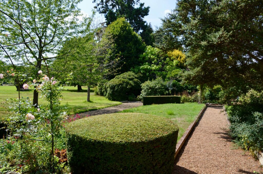 Clipped hedges and a gravel path dividing an English garden into separate areas