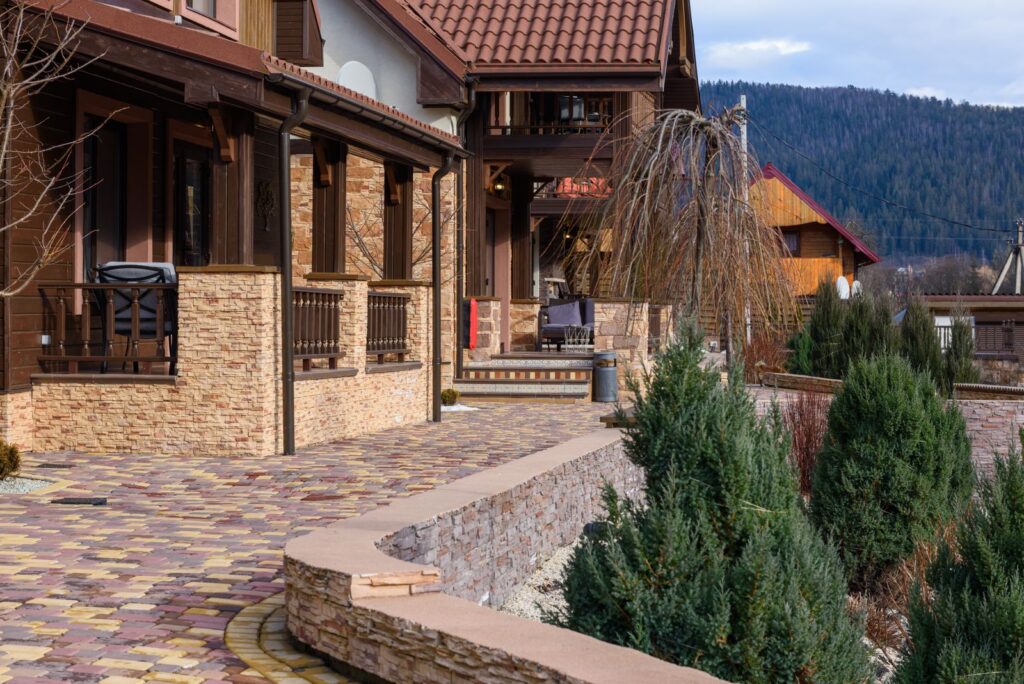 Paver walkway beside a curved stone planter wall leading to a house
