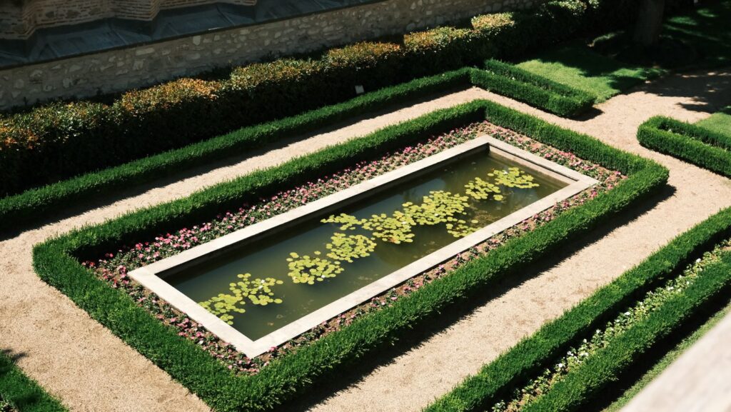 Rectangular lily pool framed by clipped boxwood hedges, seen from above