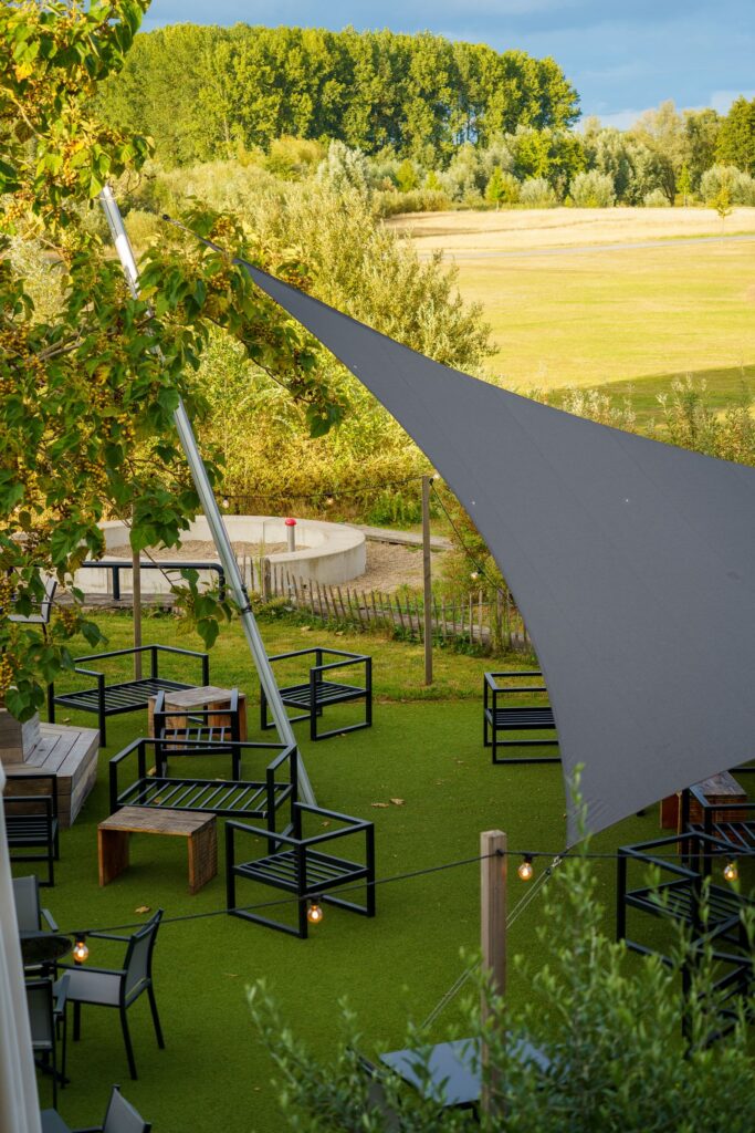 A large triangular shade sail over outdoor seating on a lawn