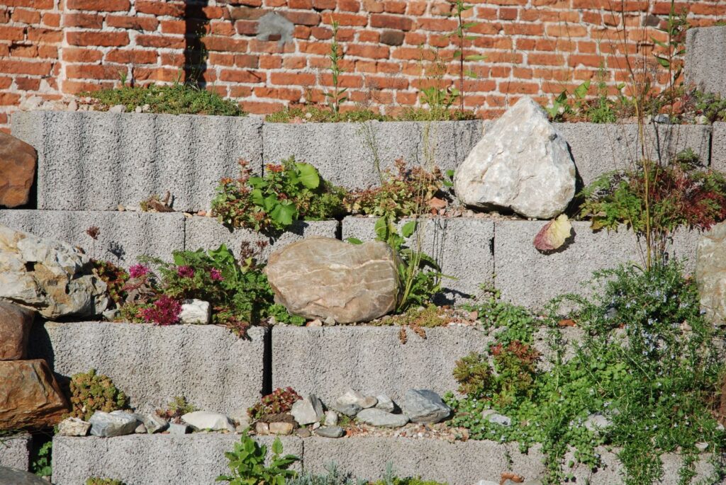 Stepped stone retaining wall planted with perennials in front of a brick wall