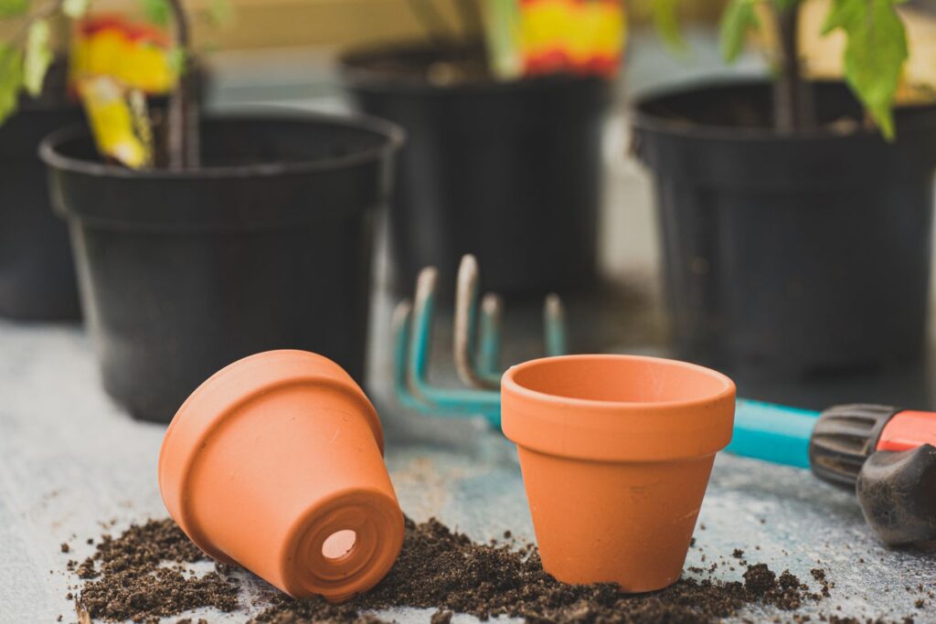Terracotta pots, soil, and a hand rake ready for container planting