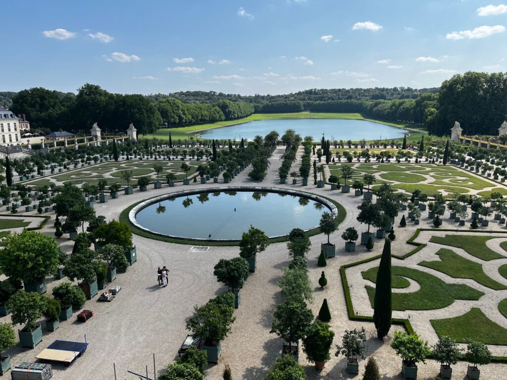 Symmetrical parterre, round pool, and lake in the gardens of Versailles