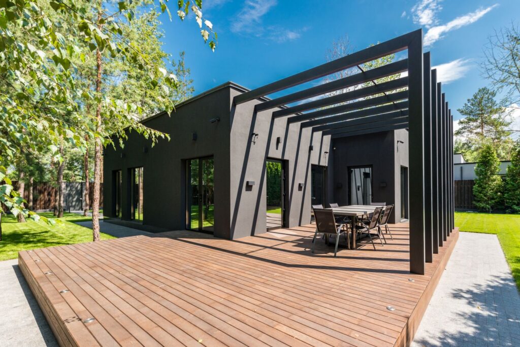 Large wooden deck with an outdoor dining set beside a modern house