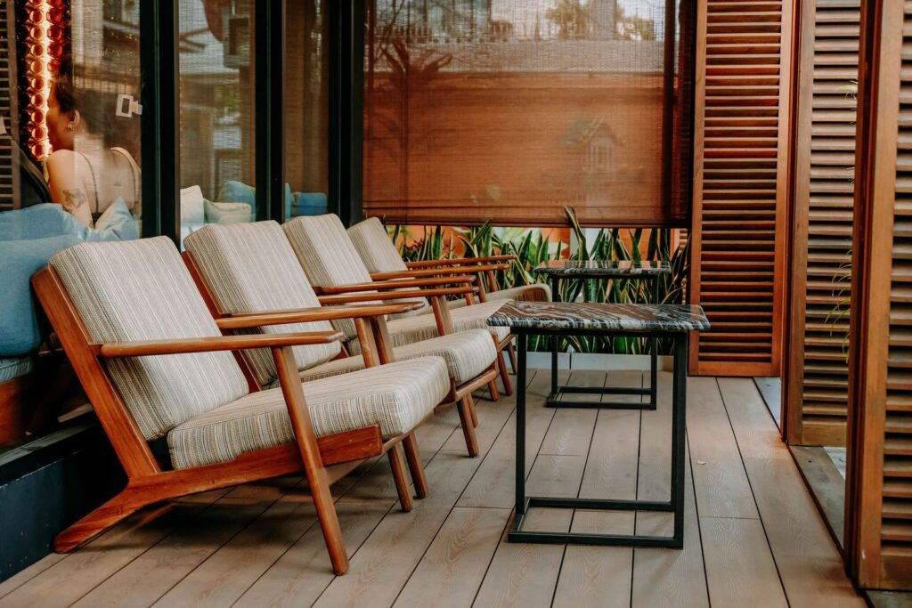 A row of wooden lounge chairs with cushions on a covered terrace