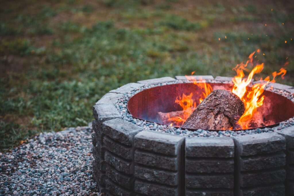 A fire burning in a ring of concrete blocks on a gravel base