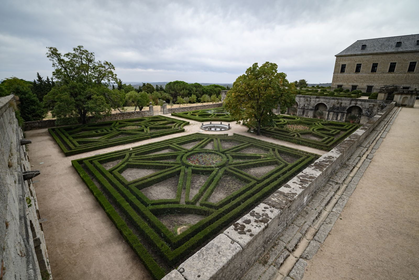 Boxwood hedges clipped into a geometric parterre beside a stone palace