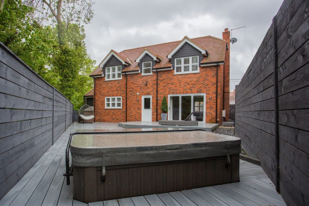 A covered hot tub on a backyard deck between tall privacy fences