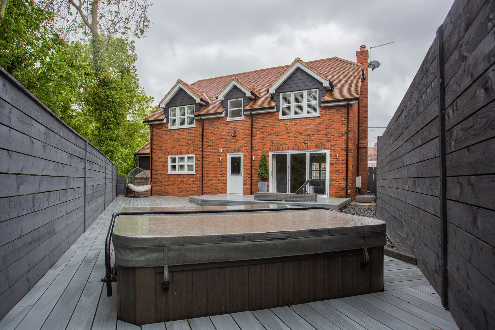 A covered hot tub on a backyard deck between tall privacy fences