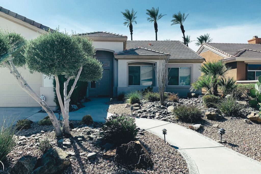 A desert front yard with gravel, boulders, shrubs and a curved walkway