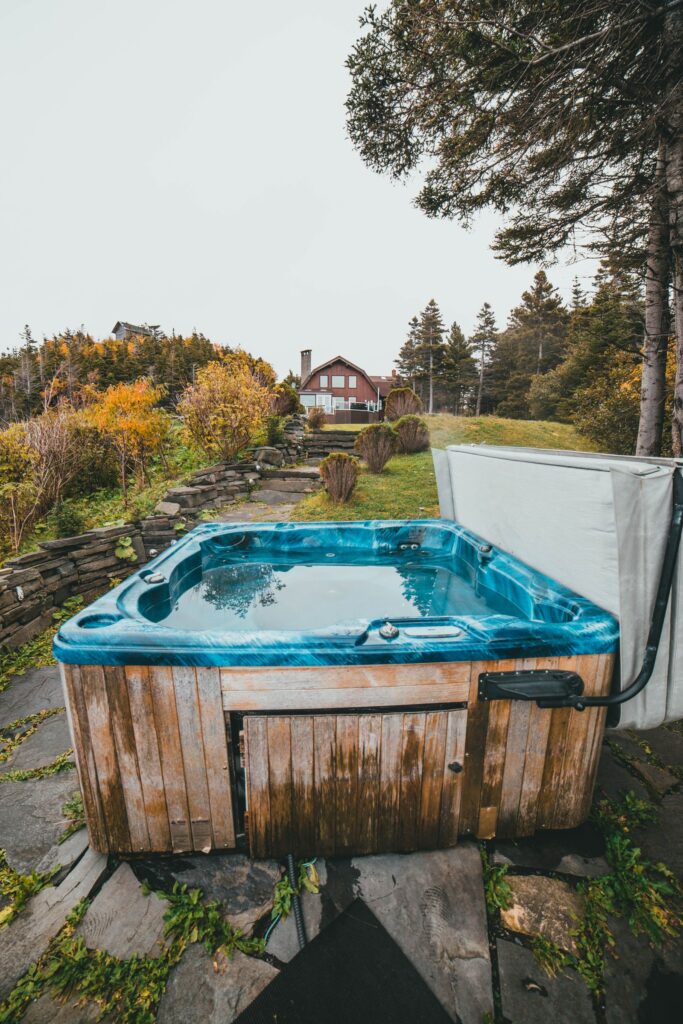 A hot tub set on a stone patio at the edge of a sloping garden