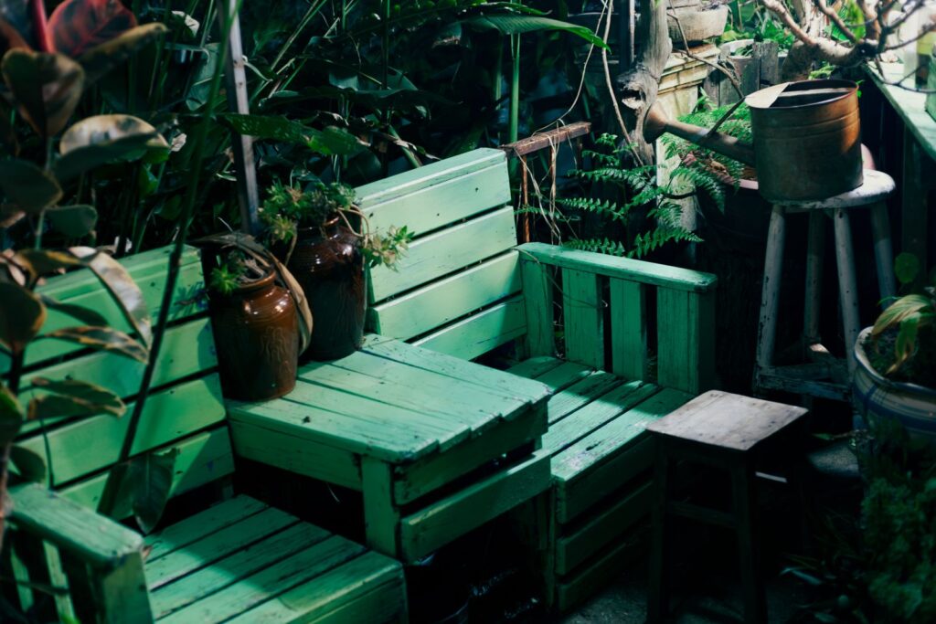 Green-painted bench and table made from wooden crates and pallets among potted plants