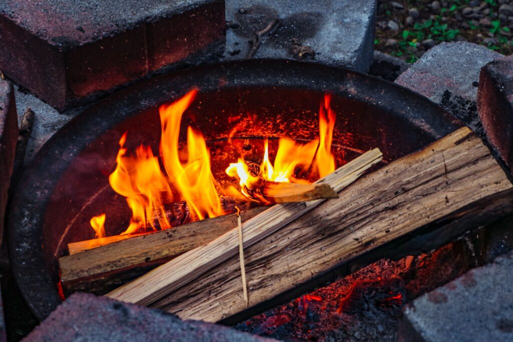 A wood fire burning inside a steel fire ring set within stone blocks