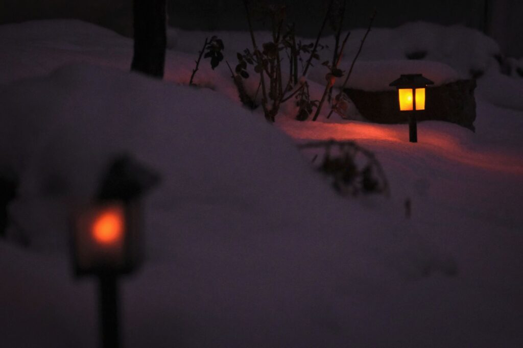 Garden lanterns glowing in deep snow at night