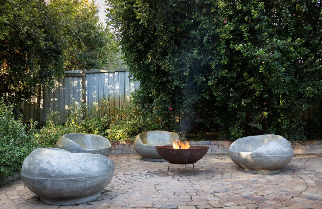 A steel fire bowl on a brick paver patio surrounded by stone seats