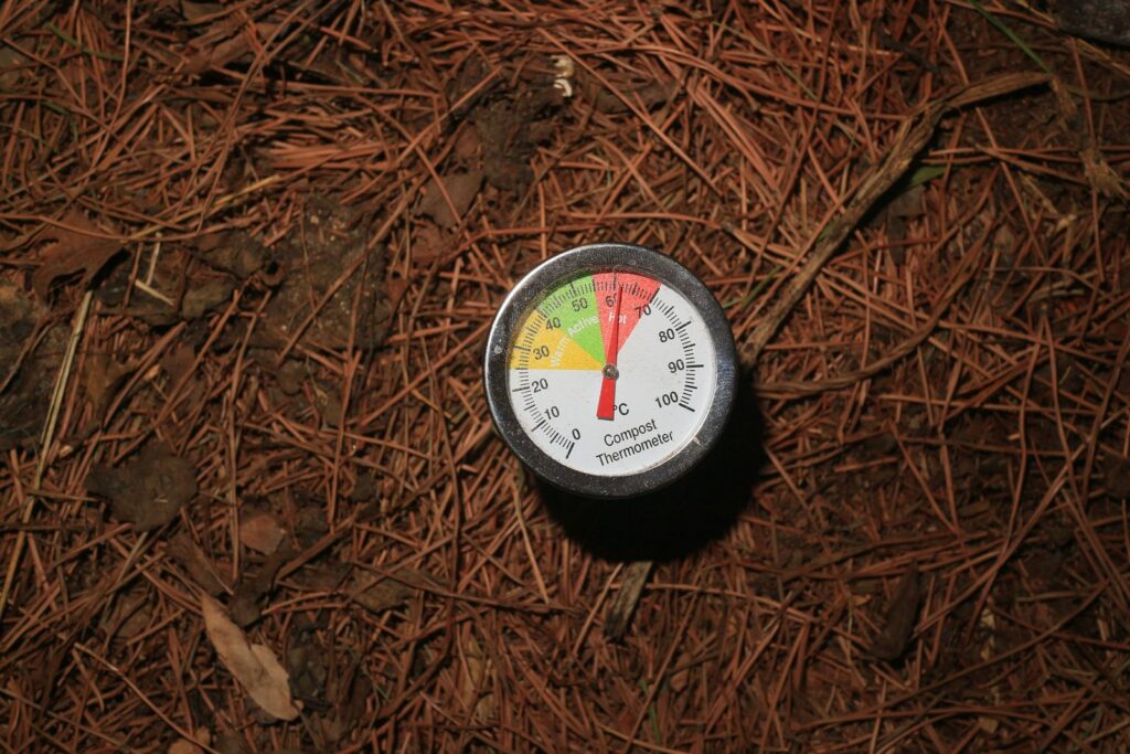 A compost thermometer pushed into a pile, showing the active temperature range