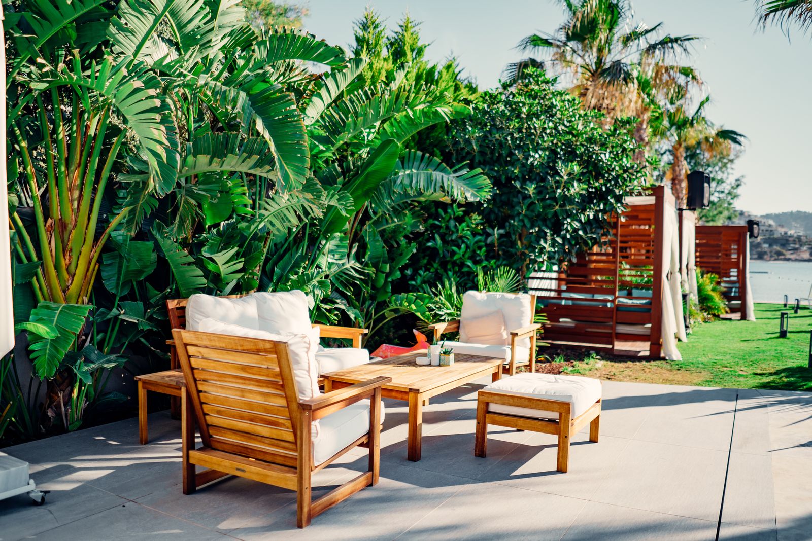 A wooden patio seating area surrounded by dense, large-leaved tropical plants