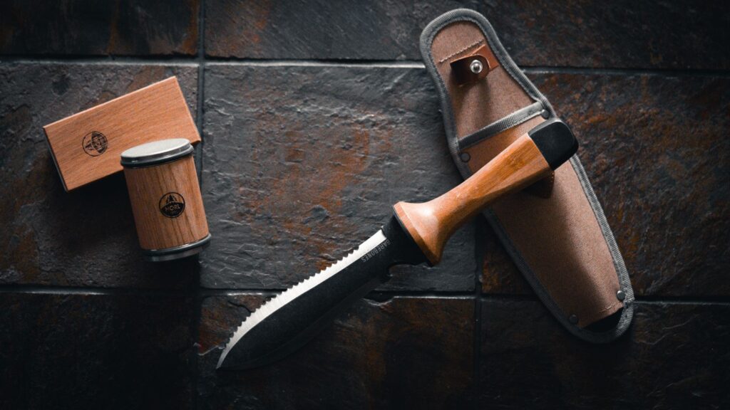 A hori-hori garden knife with a serrated edge beside its leather sheath