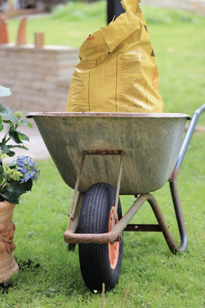 A wheelbarrow carrying a bag of soil across a lawn