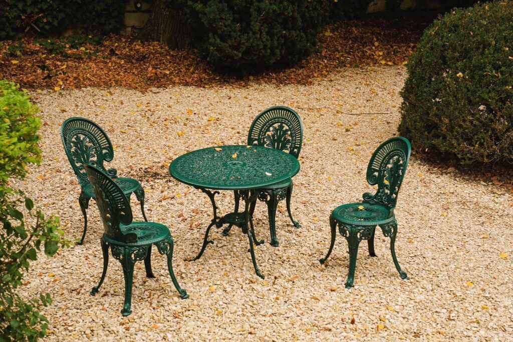 Four metal chairs and a round table on a pea gravel patio