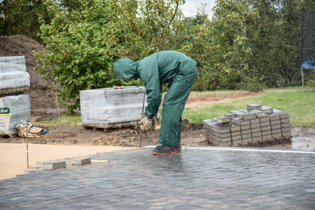 A worker setting concrete pavers on a prepared base
